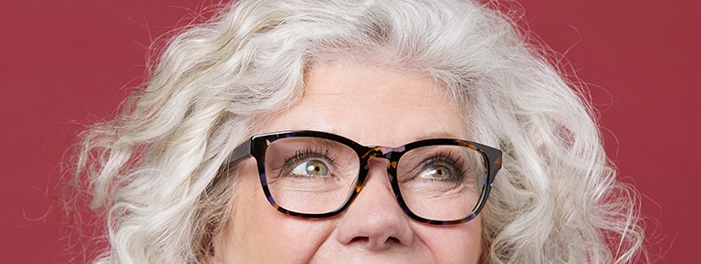 Older woman wearing glasses on red background